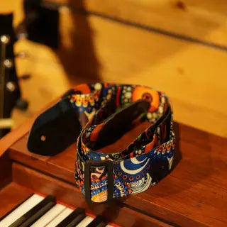 MUSICLAYA guitar strap with celestial moon and star pattern in vibrant colors displayed on wooden piano keys